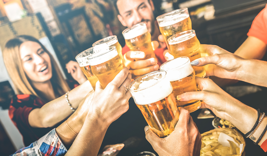 Friends drinking beer at brewery bar restaurant toasting brew pint
