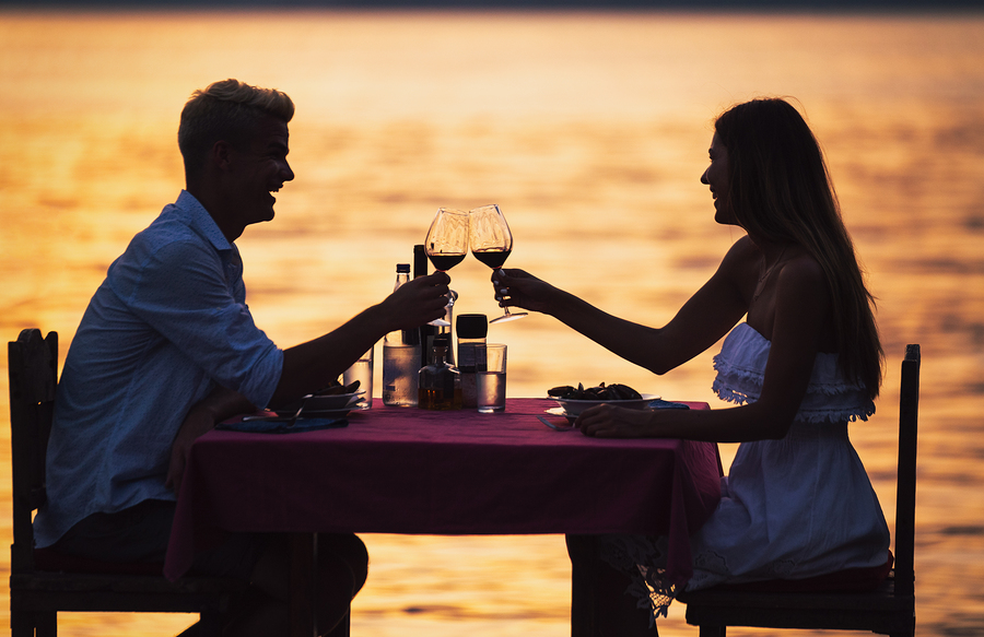 Young romantic couple toasting during dinner on tropical vacation