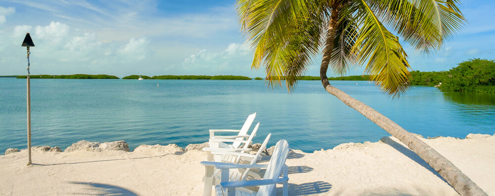 Beautiful Florida Keys along the shoreline with lounge chairs and gulf view.
