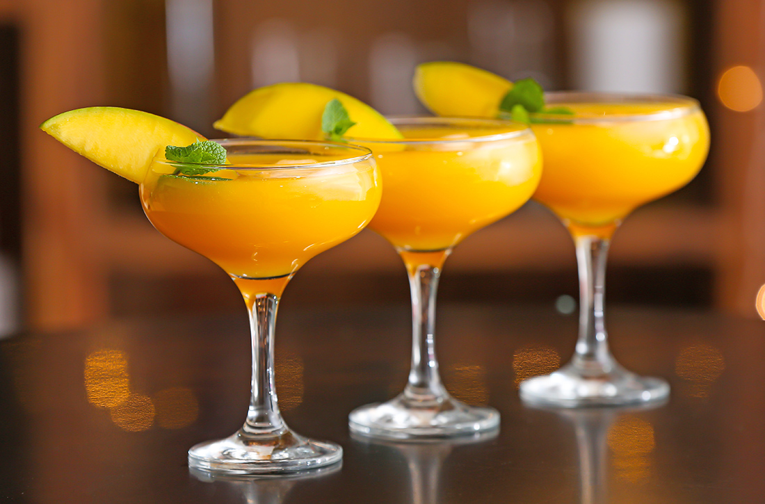 Glasses of tasty mango margarita on table in bar